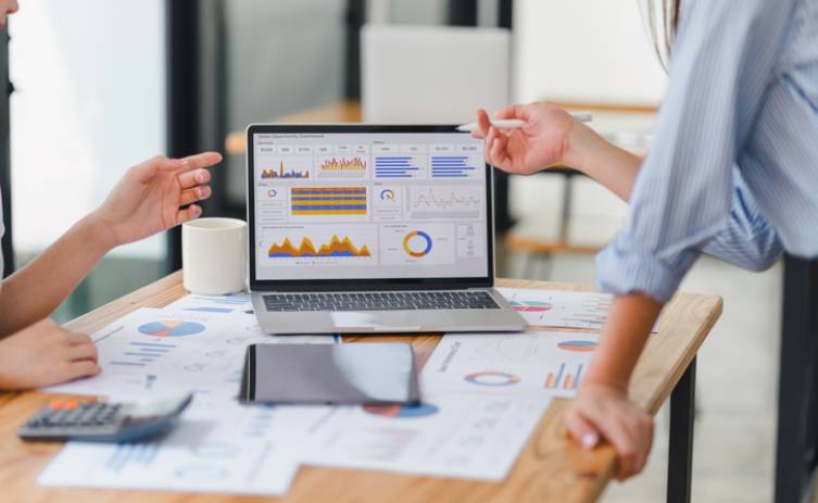 Two people are sitting at a table with a laptop.