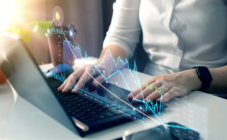 A person typing on a laptop with a graph in the background.