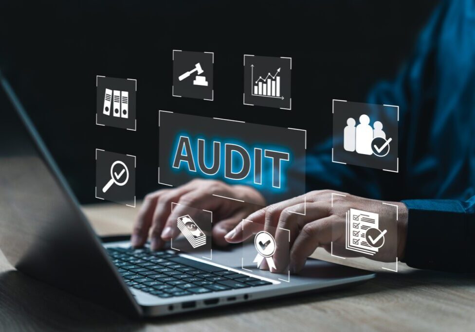 A person typing on a laptop with the word audit written in front of them.